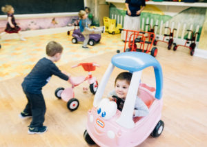 Preschool kids play with tricycles and peddle cars