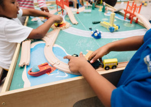 Close up of children's hands playing with toy trains