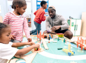 Man playing with toy trains with children