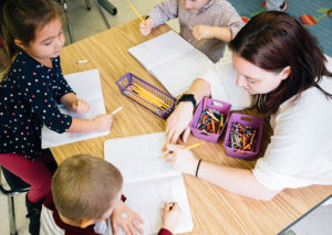 Teacher working with two preschool children at a table