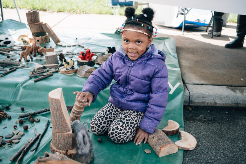 Girl playing outdoors with natural loose parts.