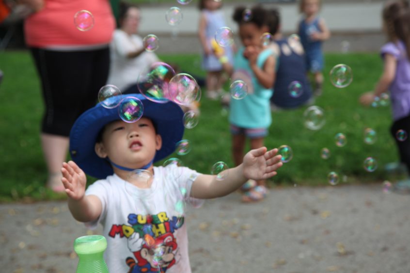 A toddler chasing bubbles in the air