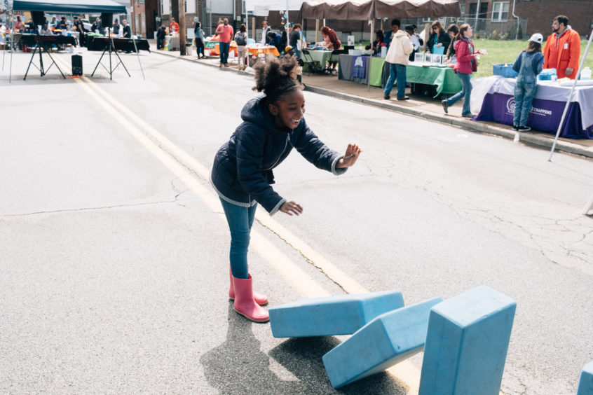 Girl pushing Imagination Playground blue blocks over like dominoes.