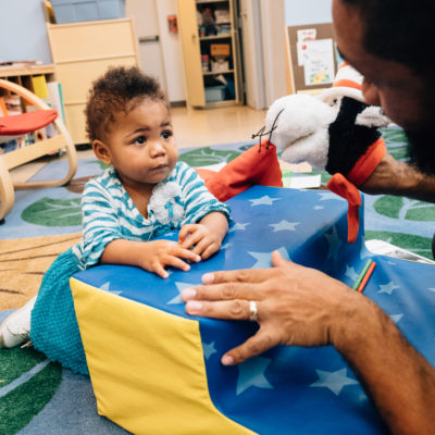 Caregiver playing with an infant in a child care
