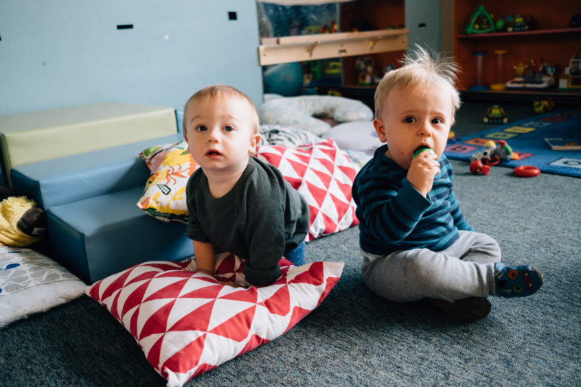 Toddler boys on floor with pillows and blocks
