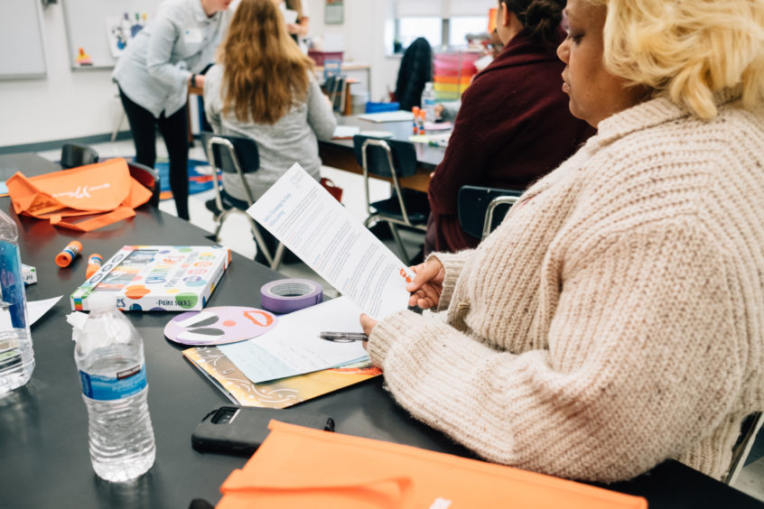 Image: An early childhood professional sits at a table, looking downward at an UnConference informational handout.
