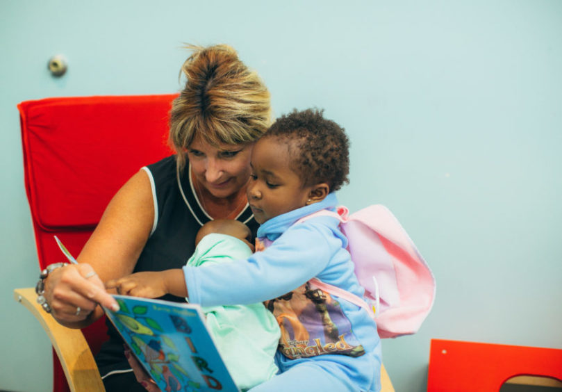 A woman and young child read together on a chair at the Homewood Early Learning Hub.