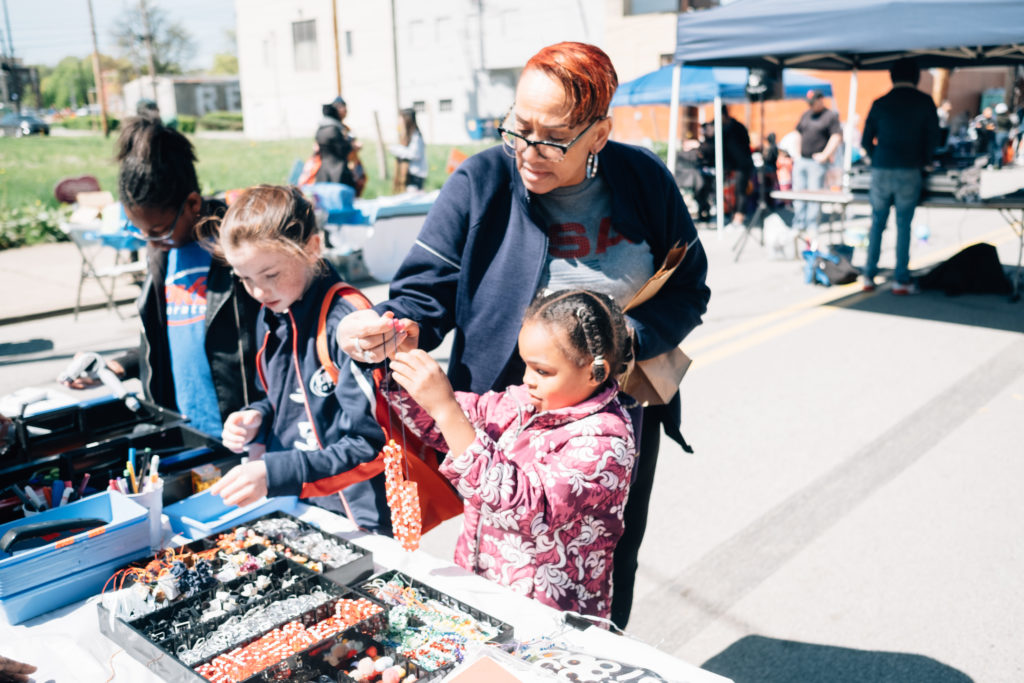 Picture: At the 2019 Homewood Block Party, children play at a craft table alongside an older adult.