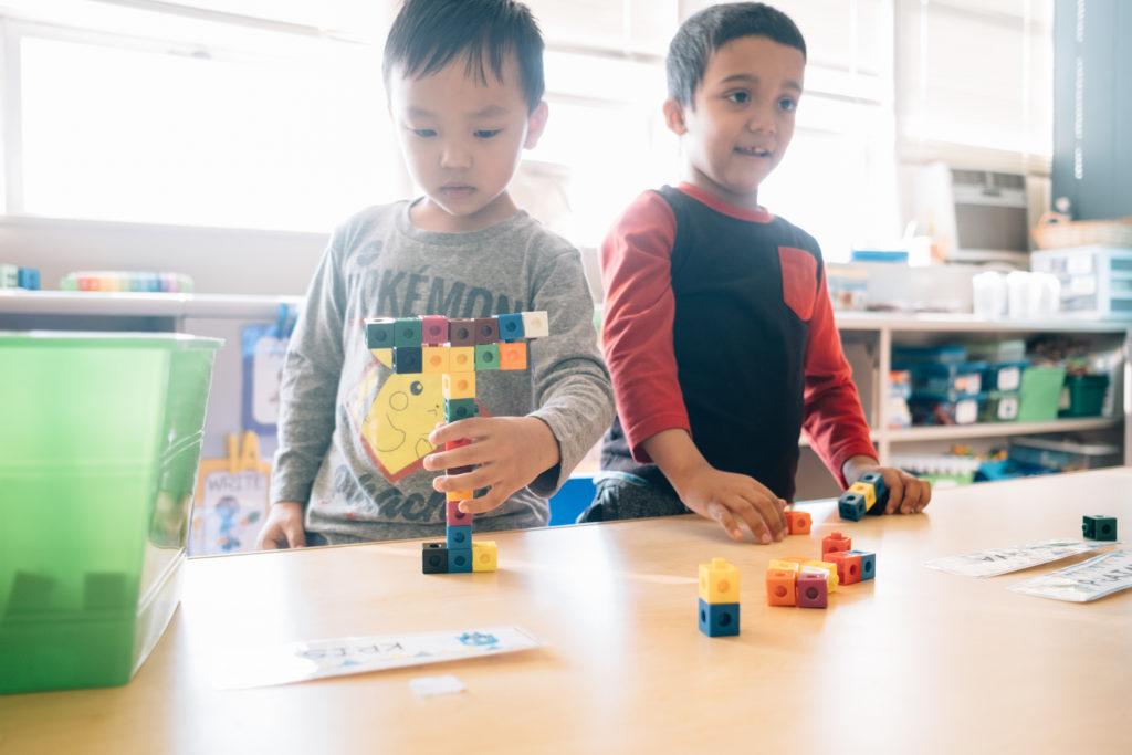 Picture: Two young boys stand at a table together playing with attachable blocks.
