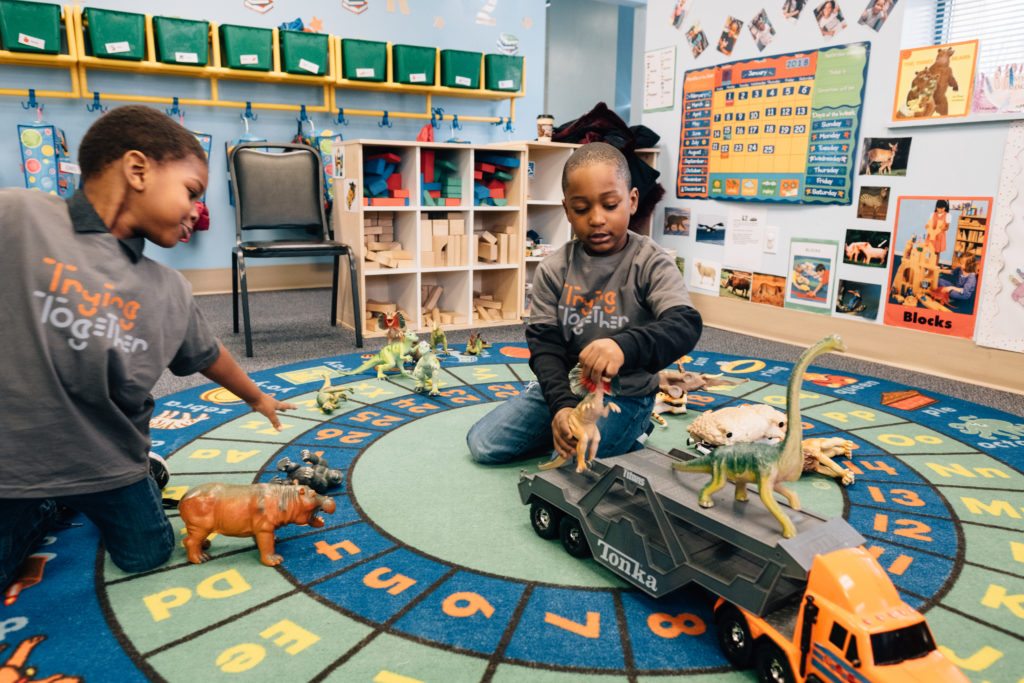 Image: Two young children kneel on the floor together, playing at the Homewood Early Learning Hub.