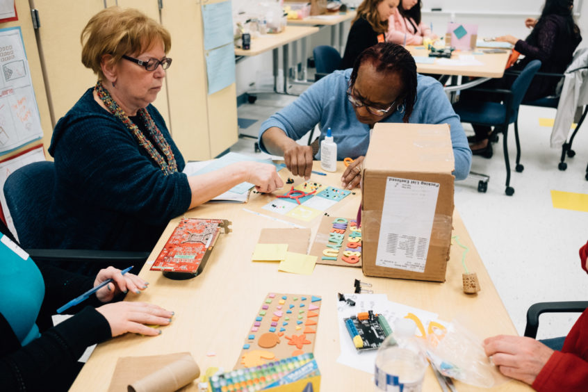 Image: Early childhood professionals sit together at Trying Together's UnConference, tinkering with tools in front of them.