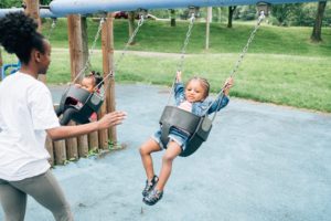 Image: A caregiver pushes her young child on a swing at a local park in Pittsburgh.