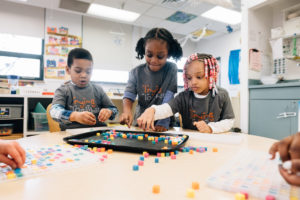 Three children playing at a table with beads | Gender expressions
