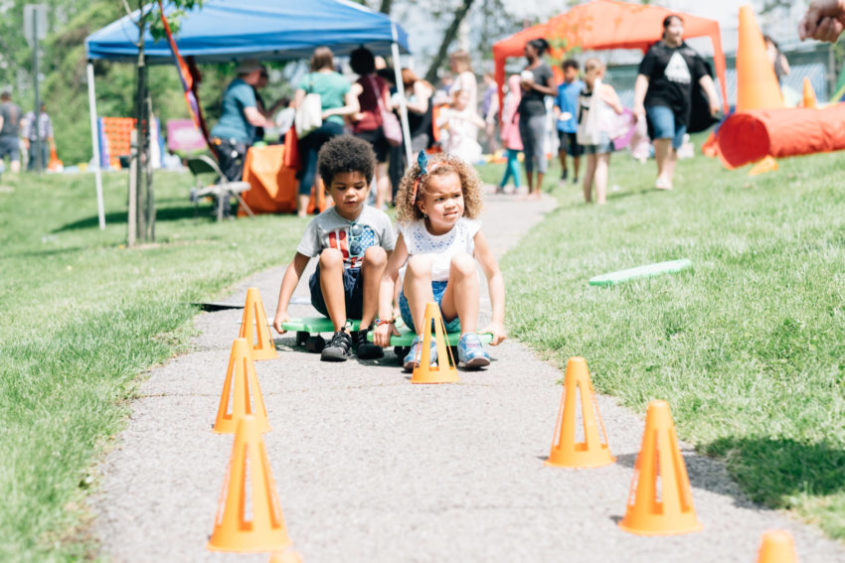 Two children sitting on side walk next to orange cones | gender identity