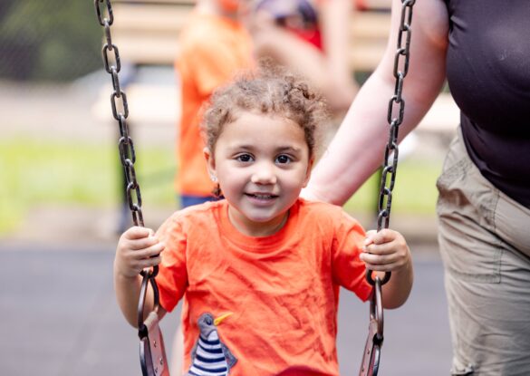 August Recalls on Children’s Products | Young child smiling sitting on a swing