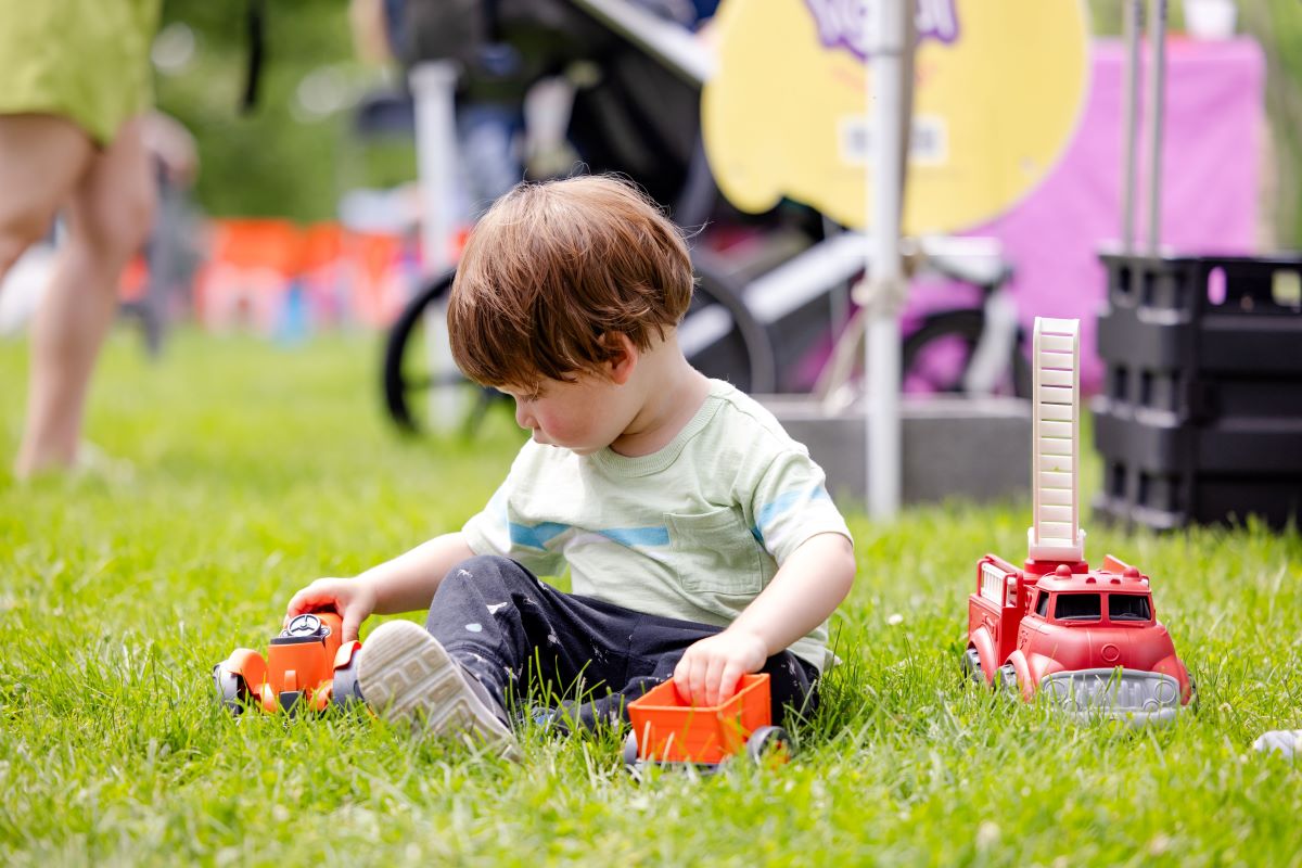 Child sitting in grass playing with trucks | Childs Cognitive development