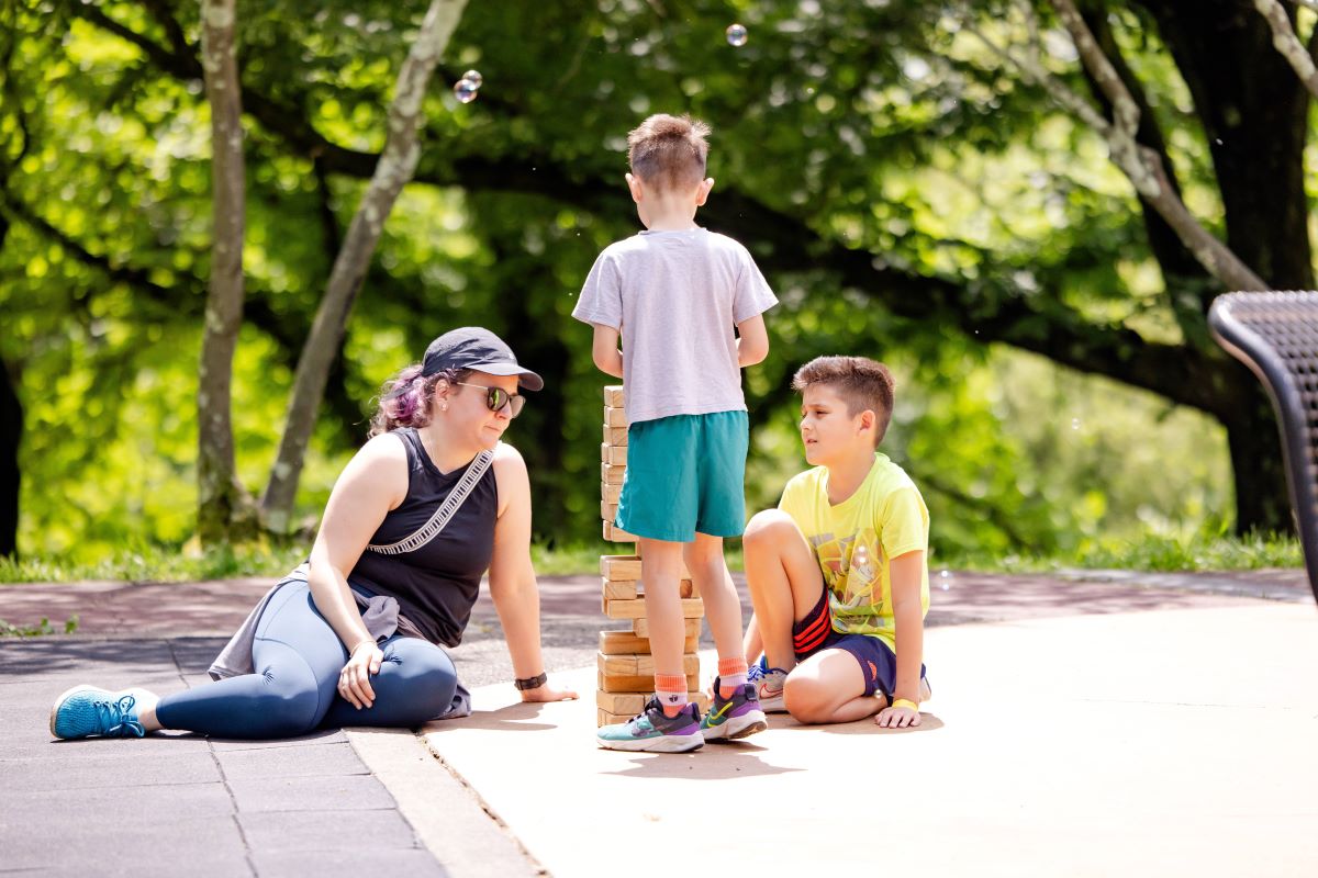 A woman playing giant Jenga with two children | Let's Play