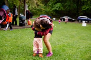 A woman leaning down and hugging a child | The Transformative Power of Play in Society